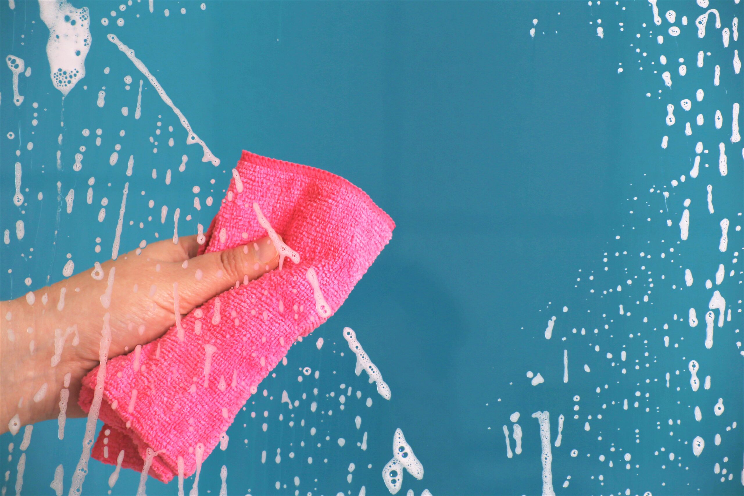 Bayeta rosa siendo utilizada para limpiar la mampara de la ducha