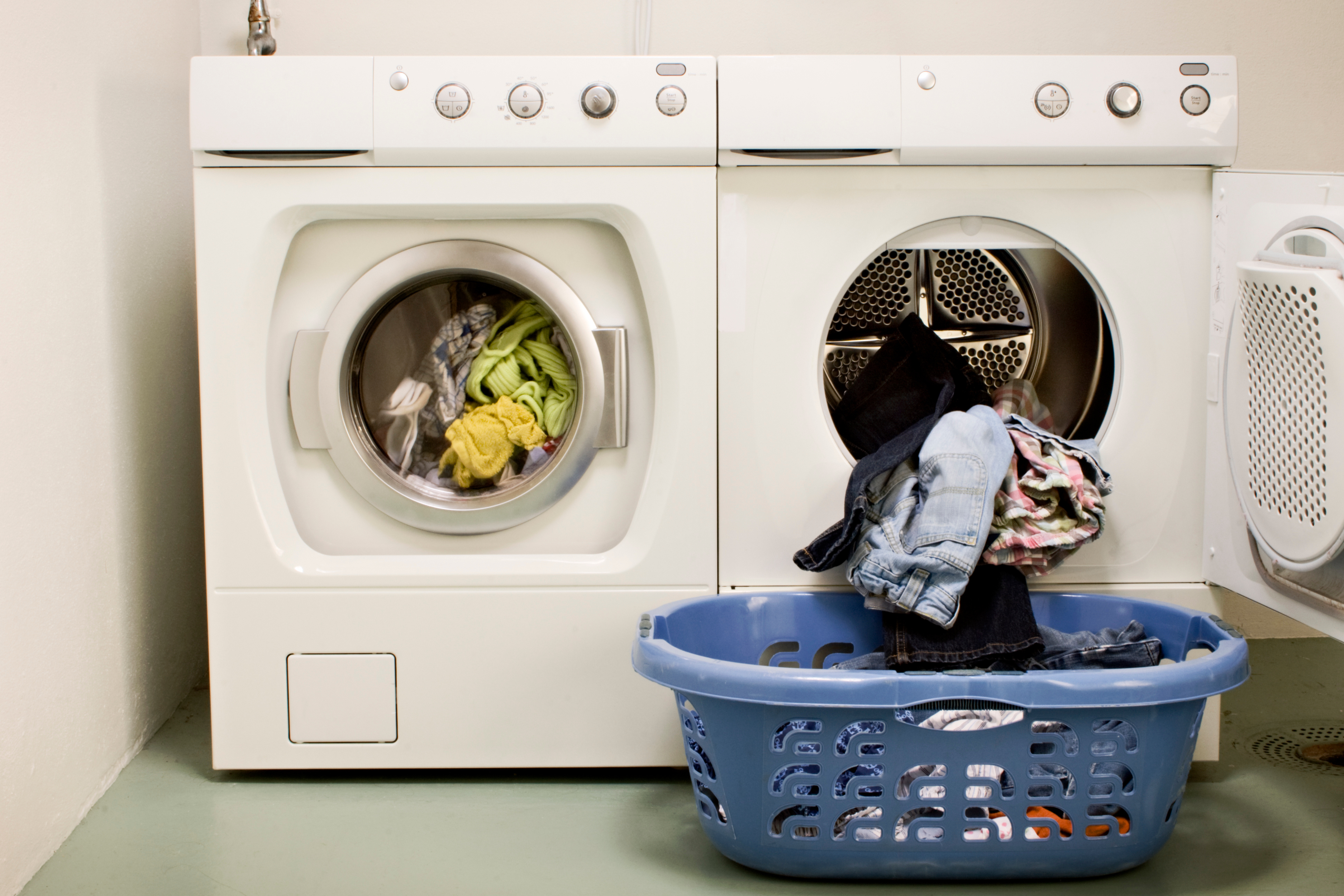 Secadora abierta con una cesta de ropa limpia al lado, representando el cuidado y mantenimiento necesario para evitar malos olores