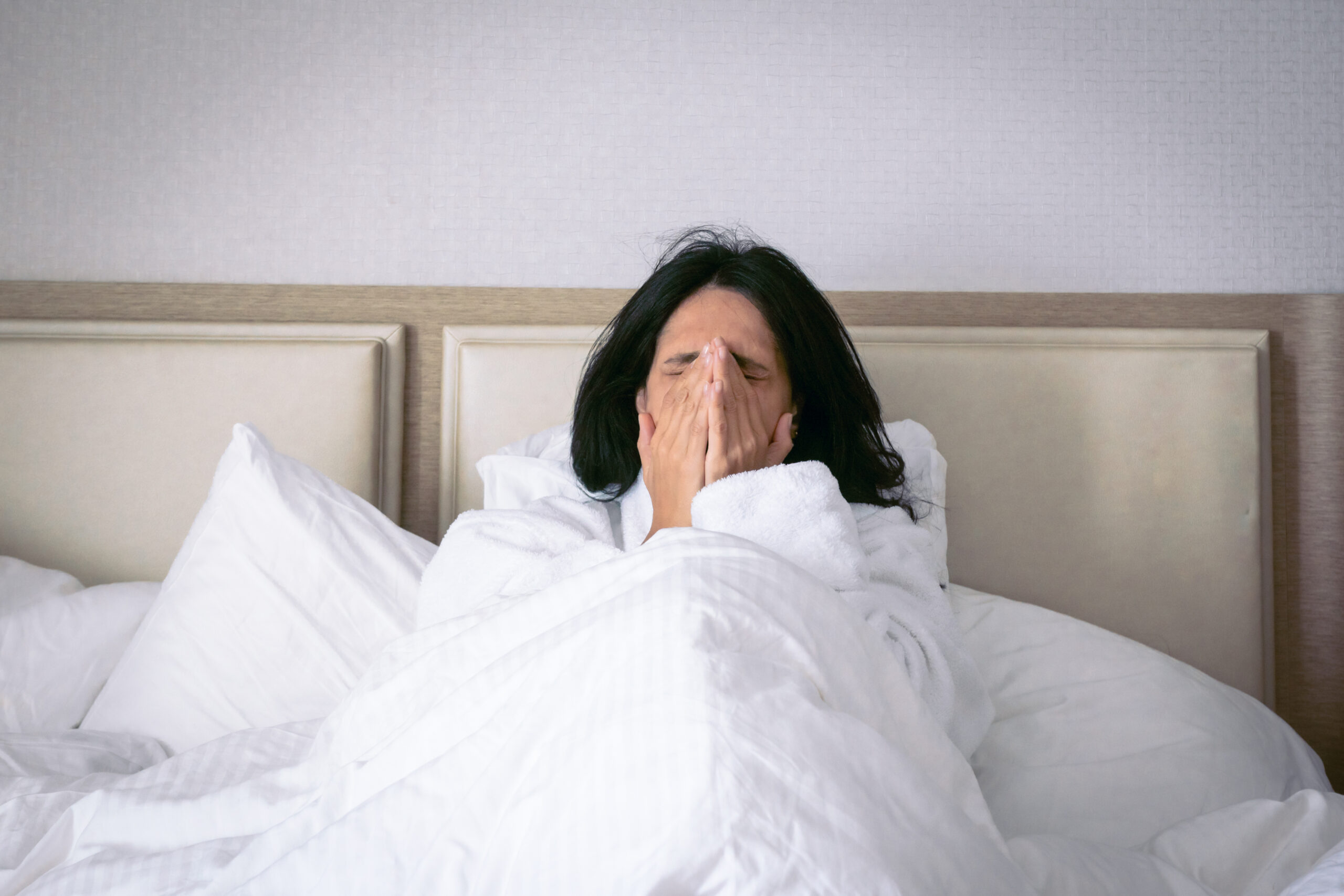 Mujer estornudando en la cama, sugiriendo la presencia de ácaros, en contexto con el post de detección de ácaros