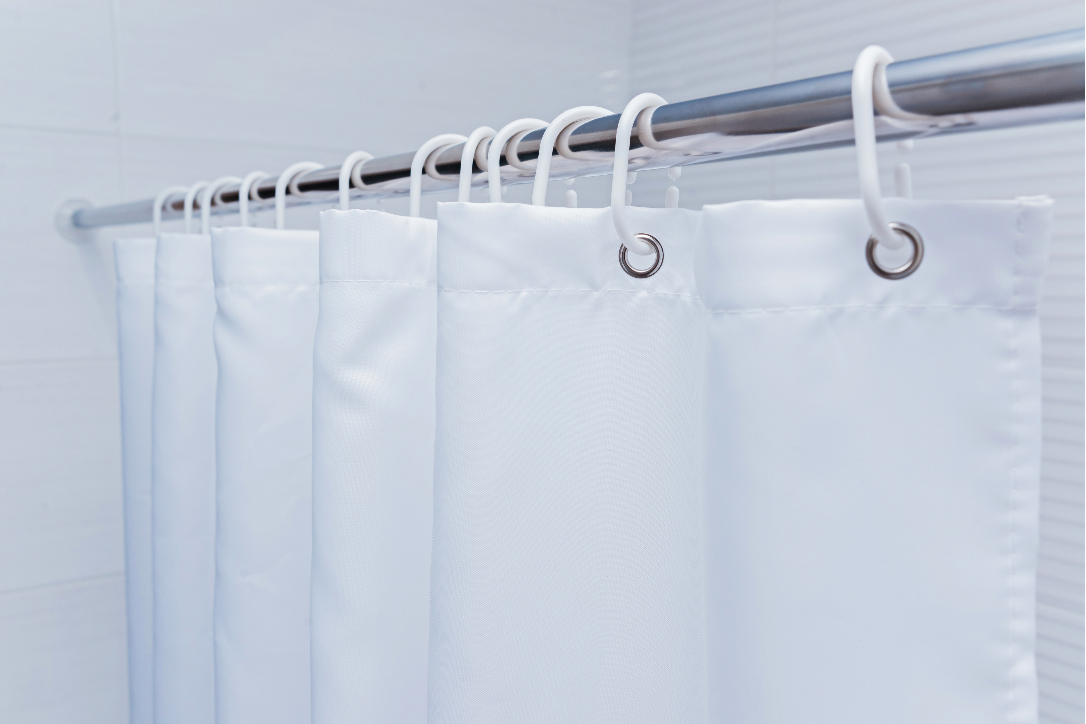 Cortinas blancas de baño, representando la importancia de su correcta limpieza y secado para prevenir el moho
